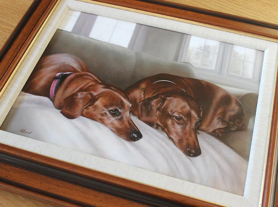 Framed oil portrait of two Dachshunds, Maggie and Max, on display.