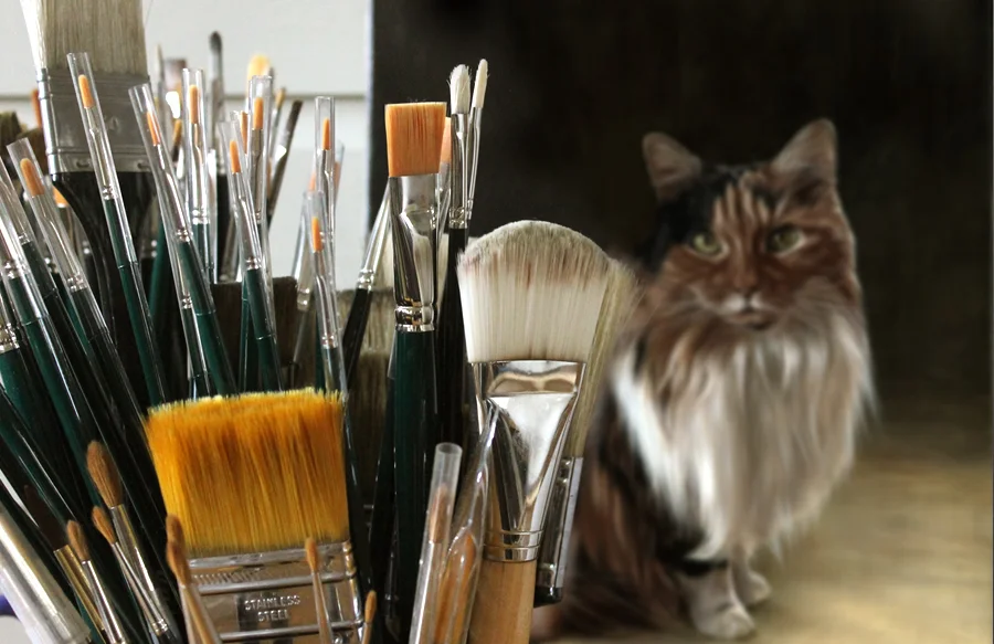 A pot filled with a diverse collection of Nicholas’s paintbrushes, including larger sizes for backgrounds, used for his cat portrait commissions.