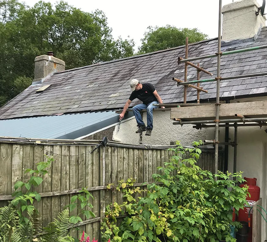Nicholas on Scaffolding During Roof Renovations Nicholas Beall on scaffolding, actively engaged in painting the roof during cottage renovations in 2019.