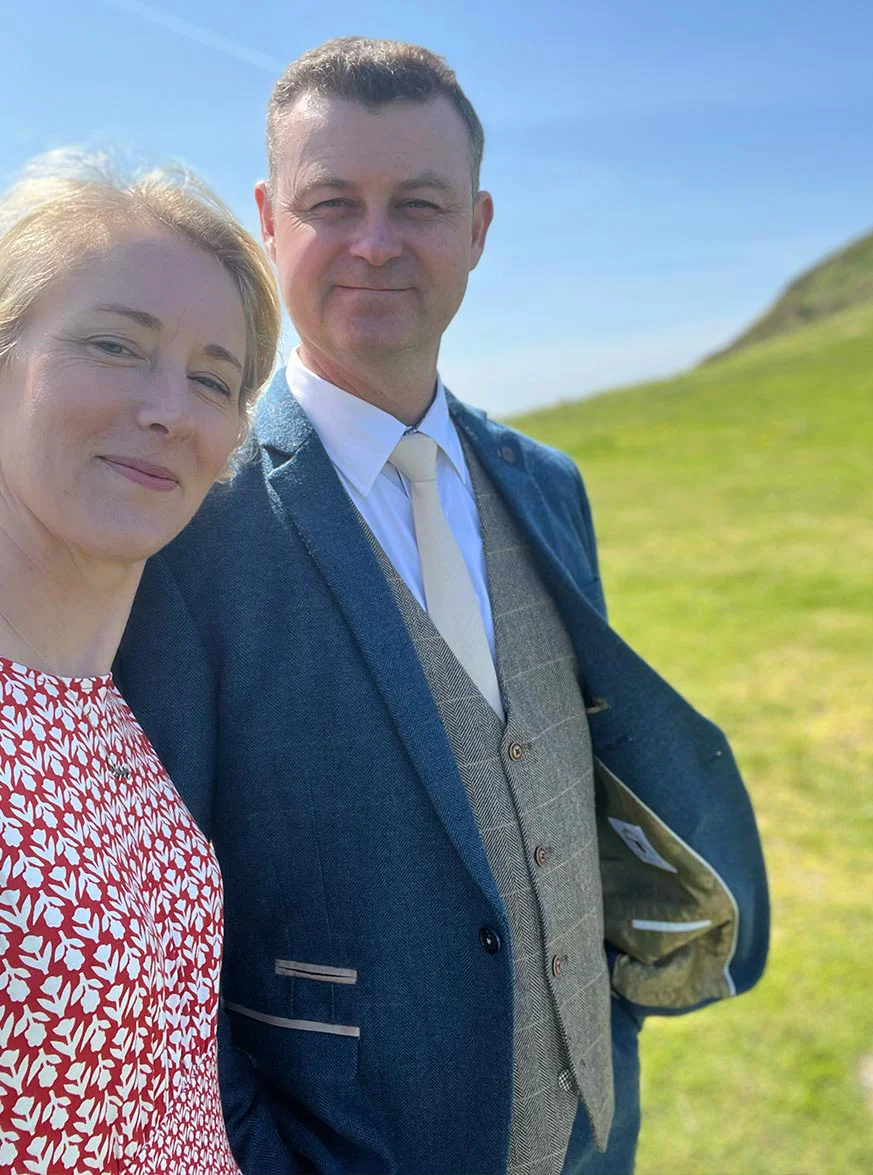Nicholas Beall – Pet Portrait Artist Nicholas Beall smiling at a wedding in Mwnt, West Wales, with the coast in the background.