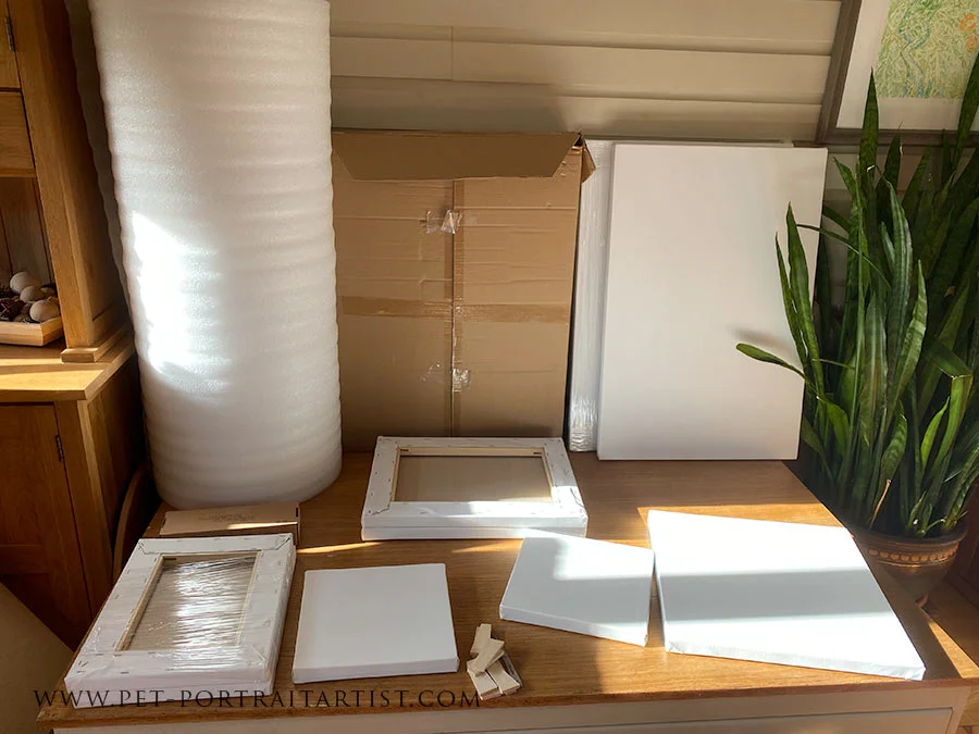 A fresh delivery of multiple custom-sized canvases stacked in the studio, indicating new pet portrait commissions are ready to begin.