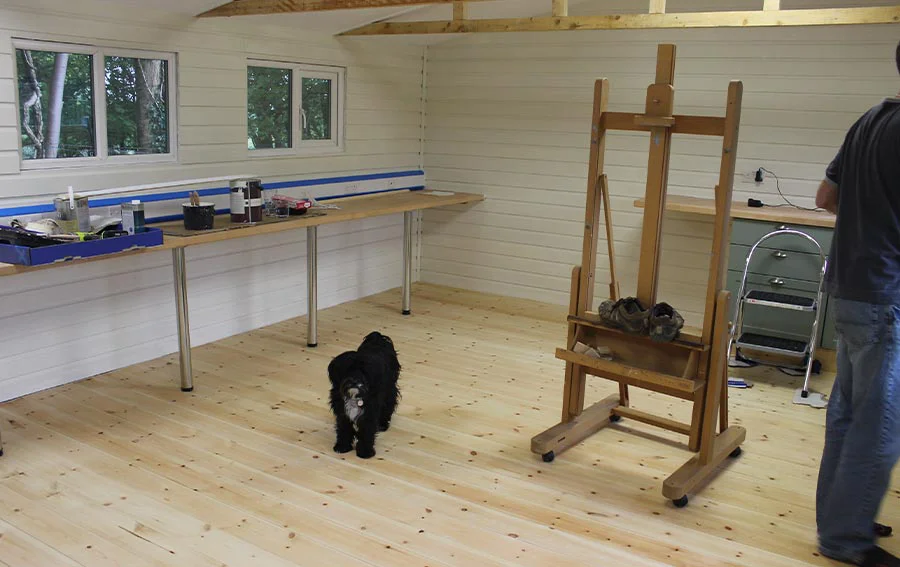 Interior shot of the studio renovation showing painted undercoat on walls, varnished floorboards, and the early stages of fitting the kitchen area.