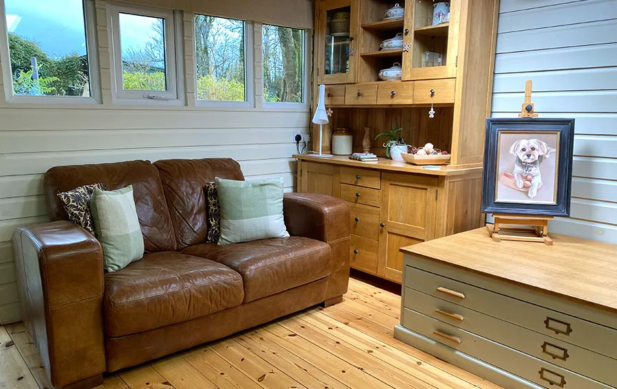 A cozy client seating area within the art studio, featuring comfortable chairs and a vintage plan chest used for storage and packing.