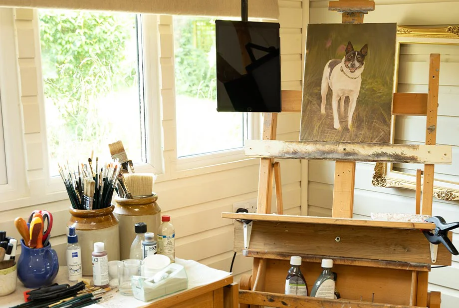 Nicholas's painting workstation in the studio, showing his easel, an oak kitchen trolley with oil paints, brushes, and mixing tools.