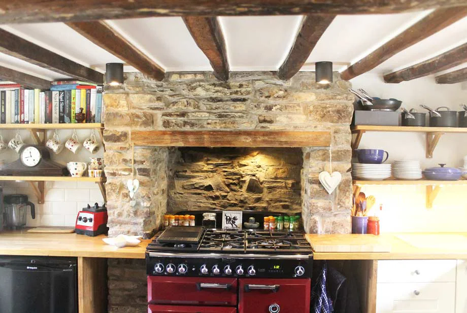Welsh Cottage Kitchen Fireplace Reopened kitchen fireplace in the Welsh cottage, featuring a reclaimed beam and a modern range cooker.